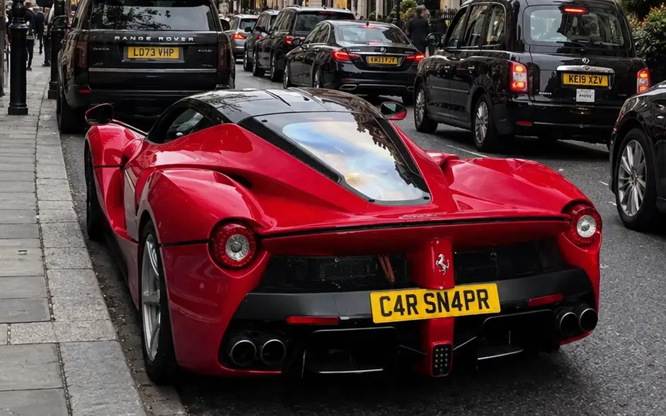 A red Ferrari LaFerrari parked in traffic on a London street.